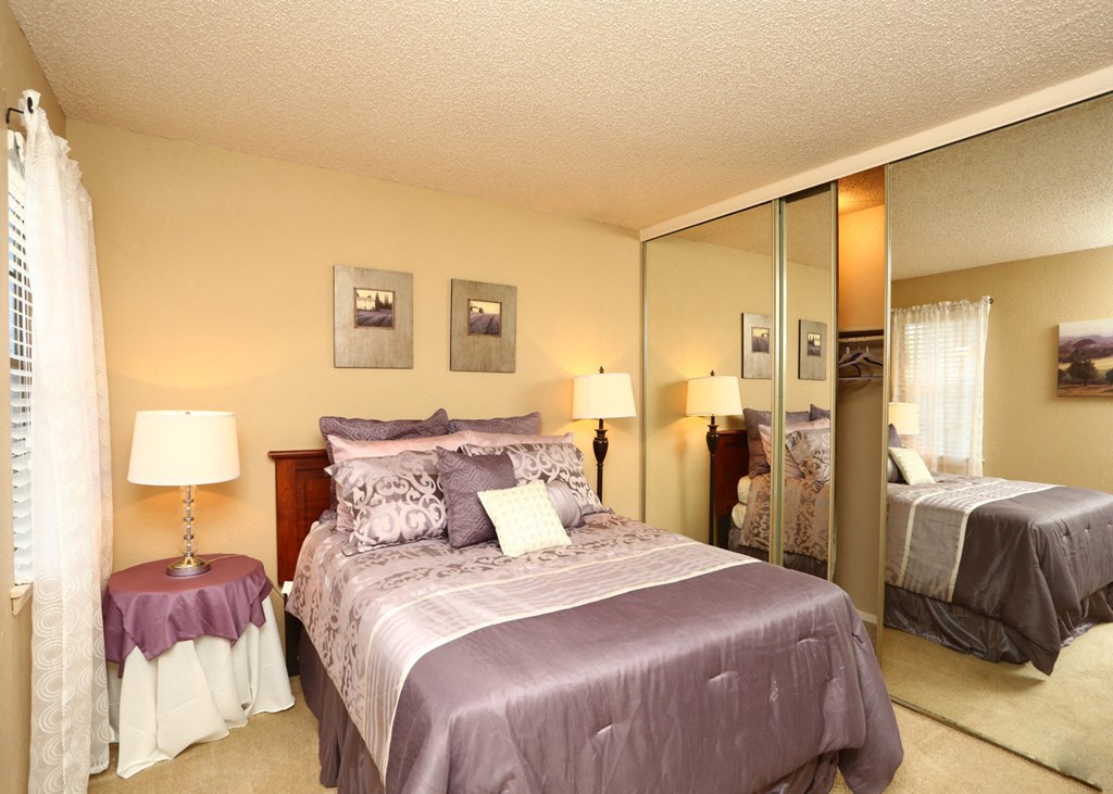 a bedroom with a large bed and a mirrored closet