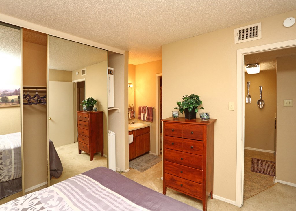 a bedroom with a bed and a bathroom with a mirror