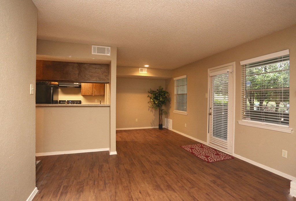 an empty living room with a door into a kitchen