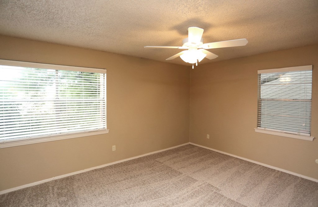 an empty bedroom with a ceiling fan and a large window