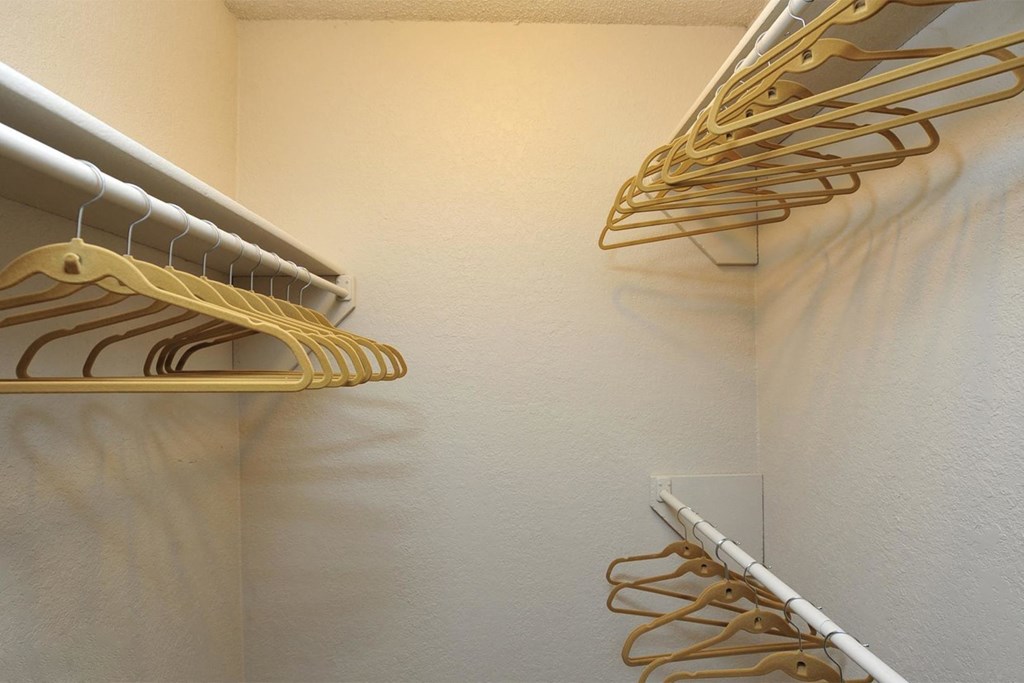 a walk in closet with a rack of clothes