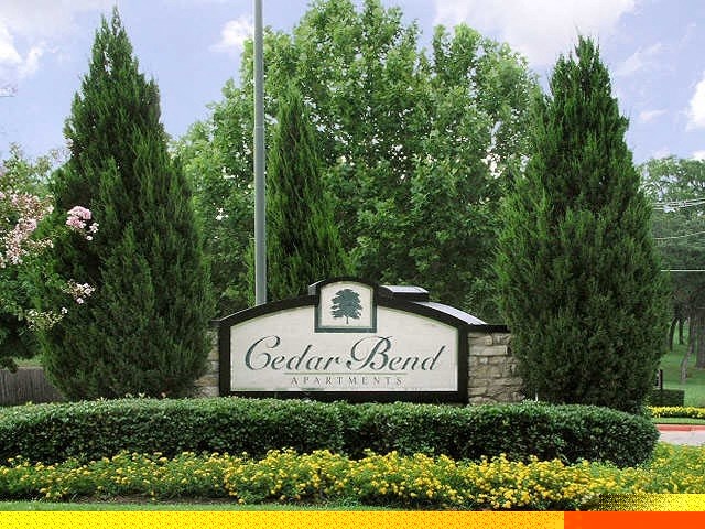 a sign for thecedar bend apartments in front of trees and bushes