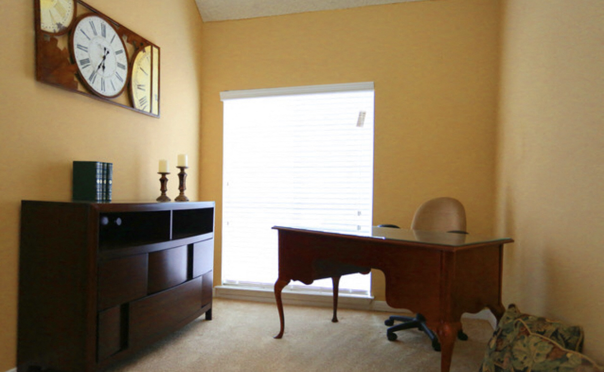 a living room with a desk and a large window