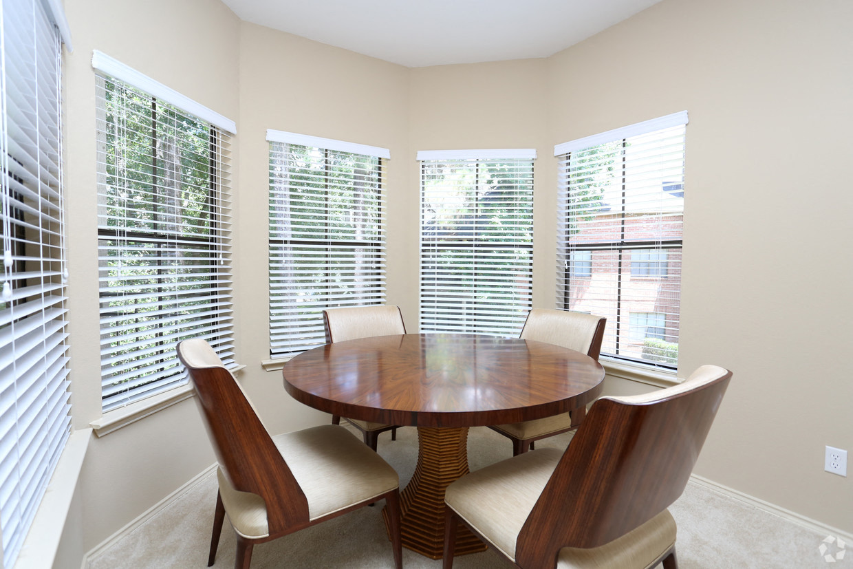 a dining room with large windows and a wooden table and chairs