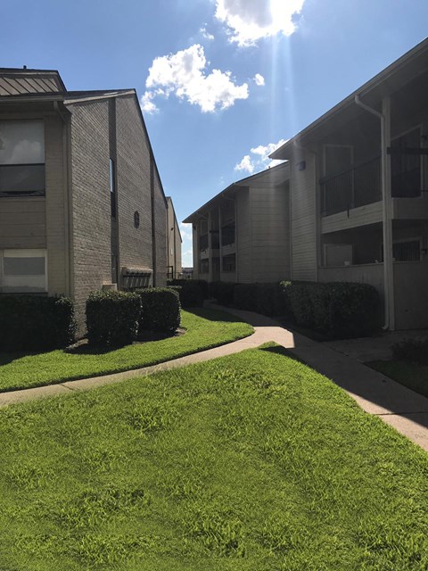 an apartment building with green grass and a blue sky