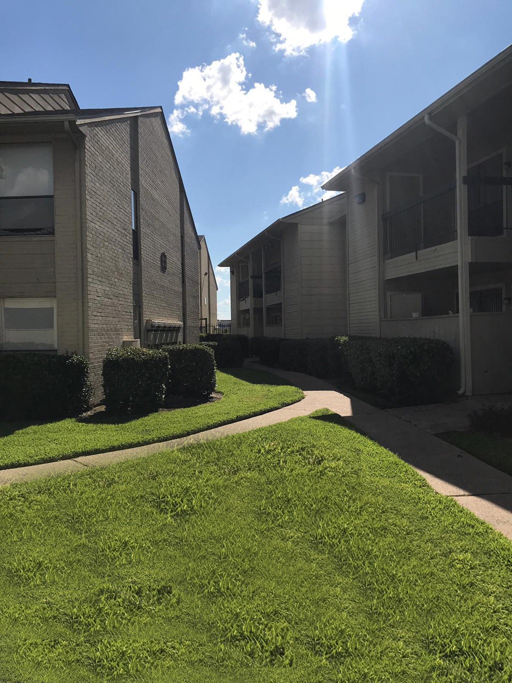 an apartment building with green grass and a blue sky
