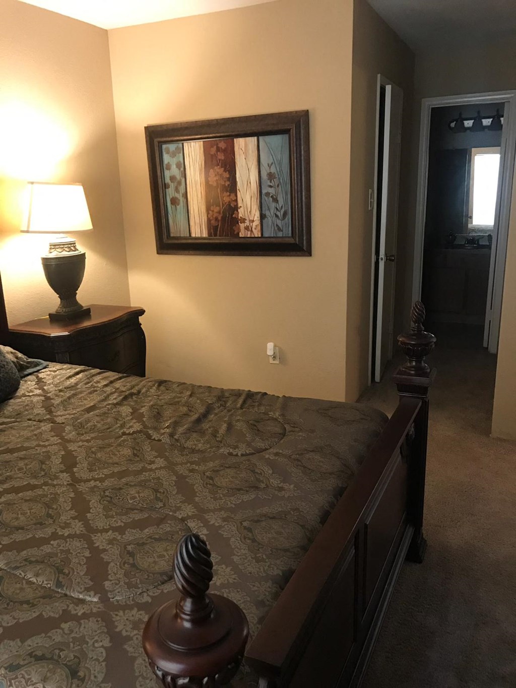a bedroom with a large bed and a painting on the wall