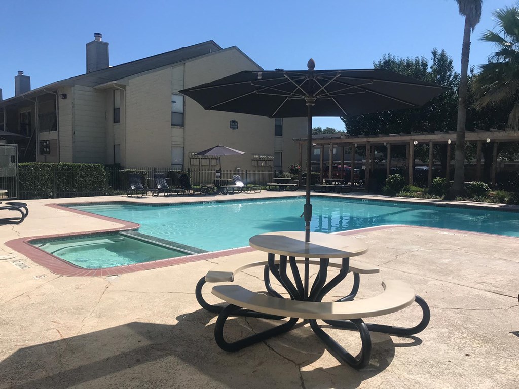 a patio table with an umbrella next to a swimming pool