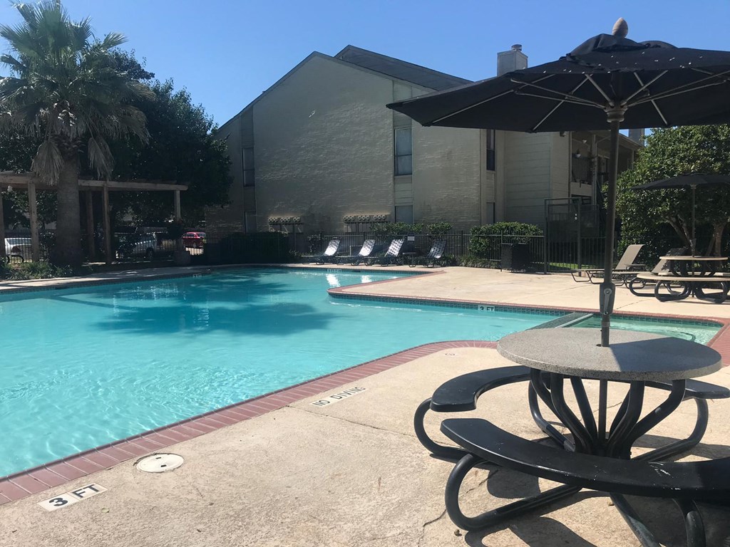 a swimming pool with a table and an umbrella in front of a building