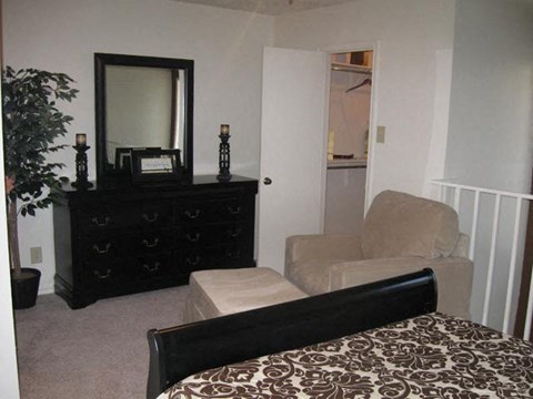 a bedroom with a couch and a chair and a mirror