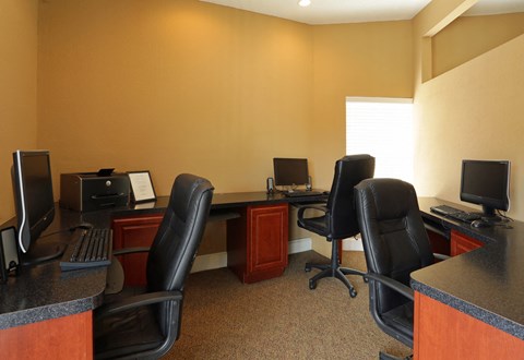 a office with three desks with computers and chairs