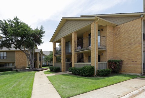 a sidewalk in front of a brick apartment building