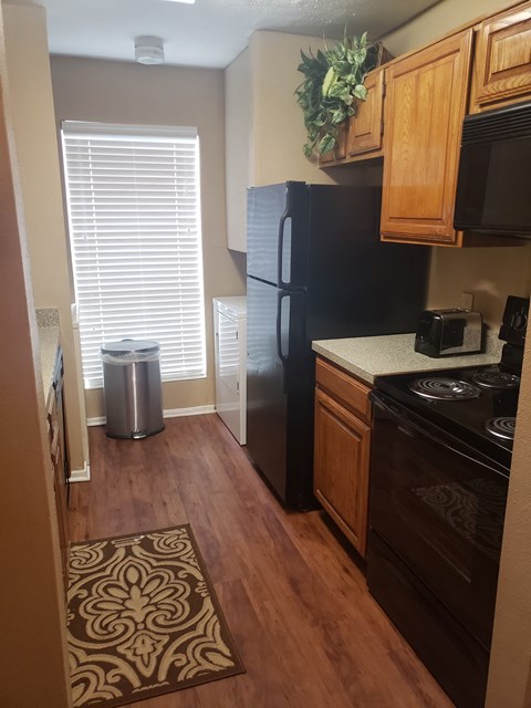 a small kitchen with a black refrigerator and a black stove