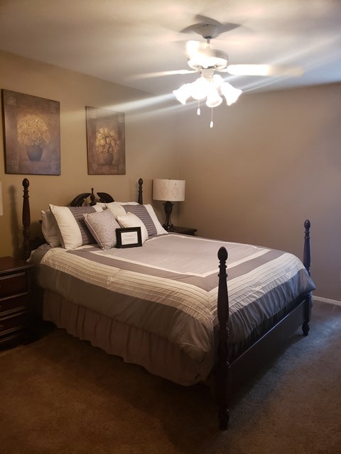 the master bedroom has a large bed and a ceiling fan