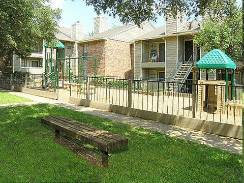 a playground with a wooden bench in front of a house