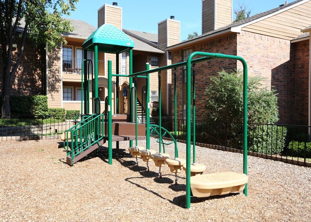 a playground with a swing set in front of an apartment building