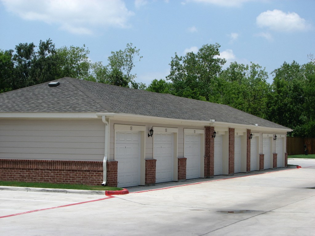 a row of white garage doors on a brick building