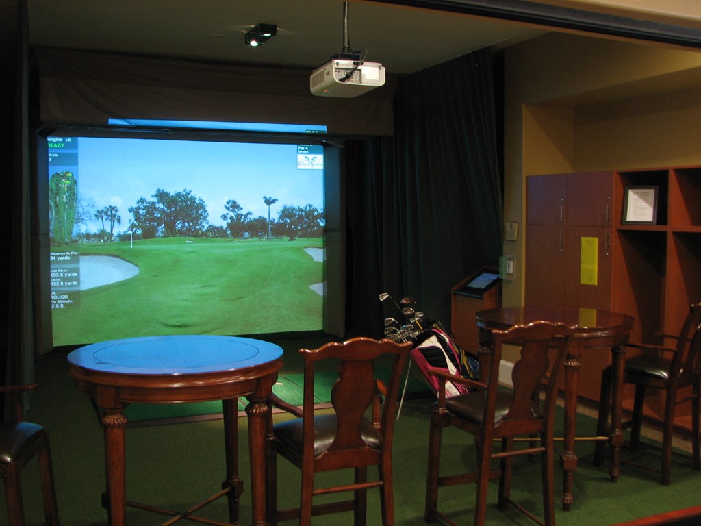 a living room with a large screen tv and a table and chairs