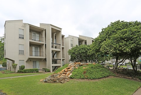 an apartment building with a rock retaining wall in the grass