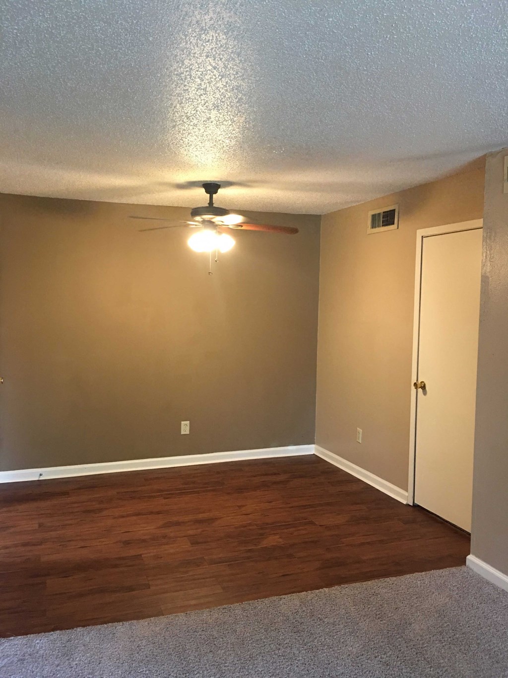 a empty room with a ceiling fan and a door