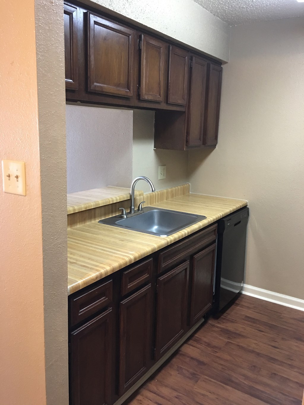 an empty kitchen with a sink and wooden cabinets