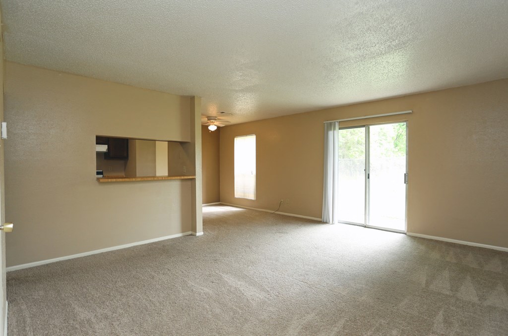 an empty living room with a tv and a door to a patio