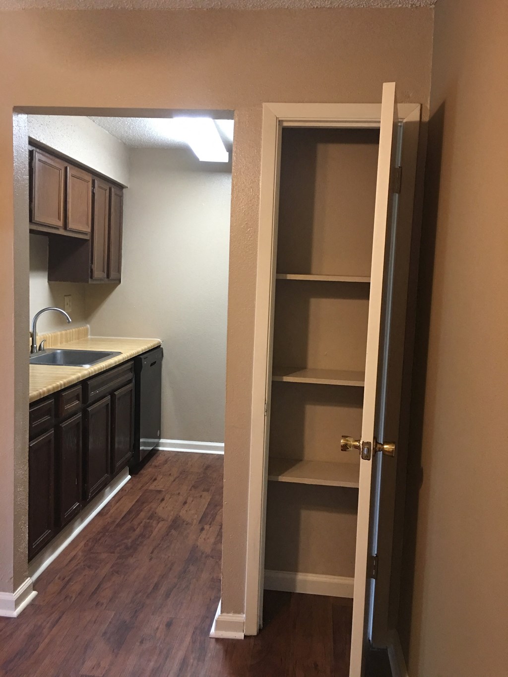 an open doorway into a kitchen with shelves and a sink