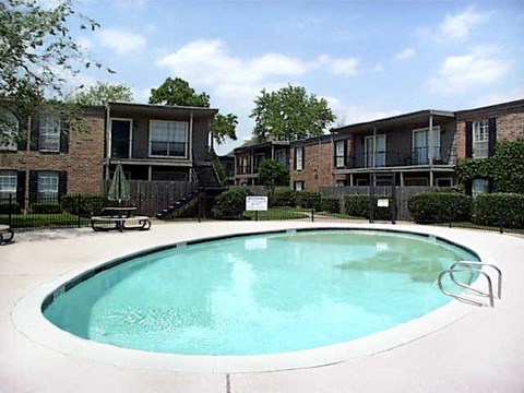 an oval swimming pool in front of an apartment building