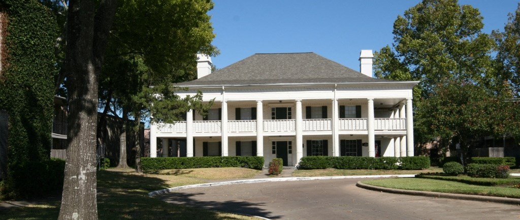a large white house with a driveway and trees in front of it