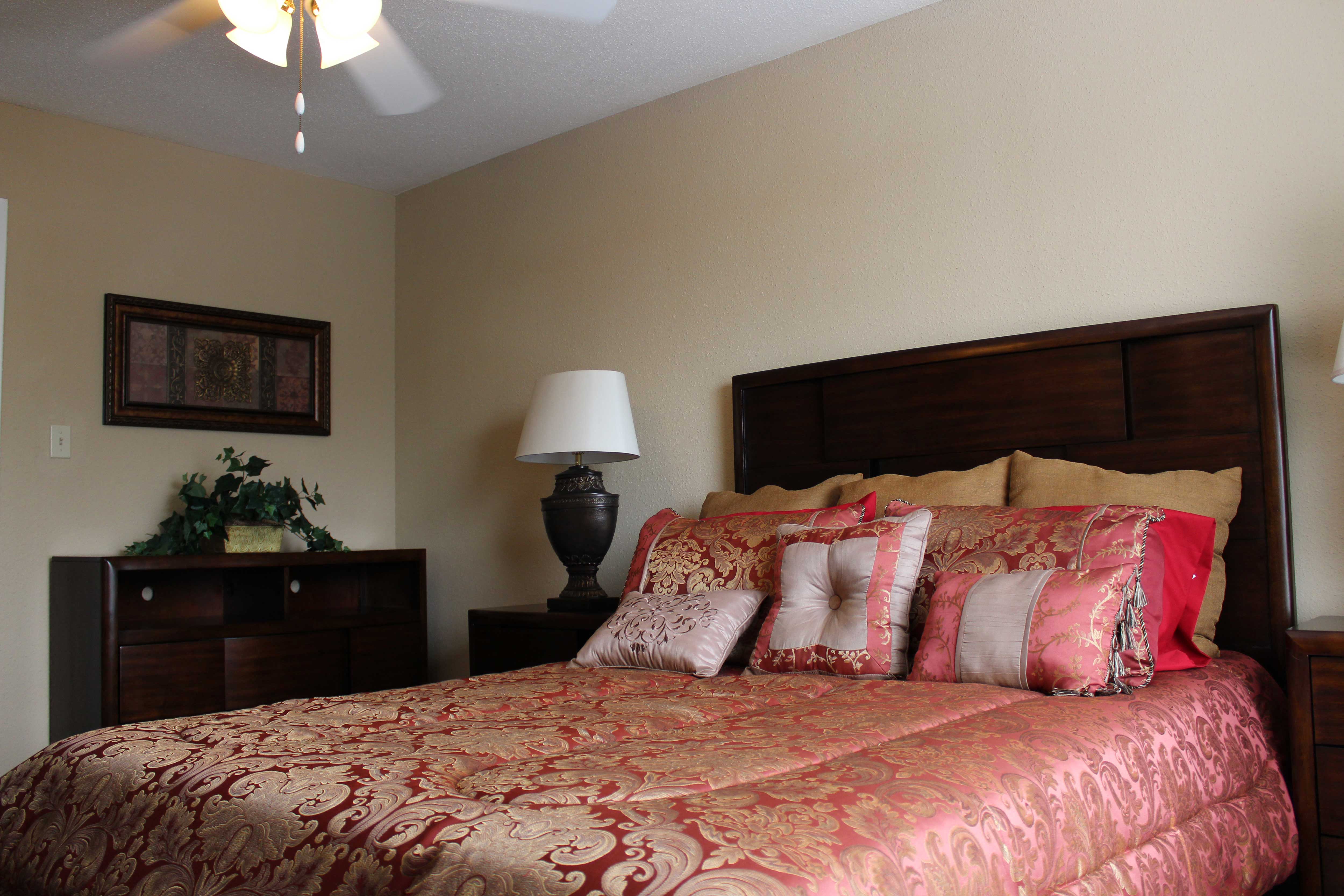 a bedroom with a bed and a dresser and a ceiling fan