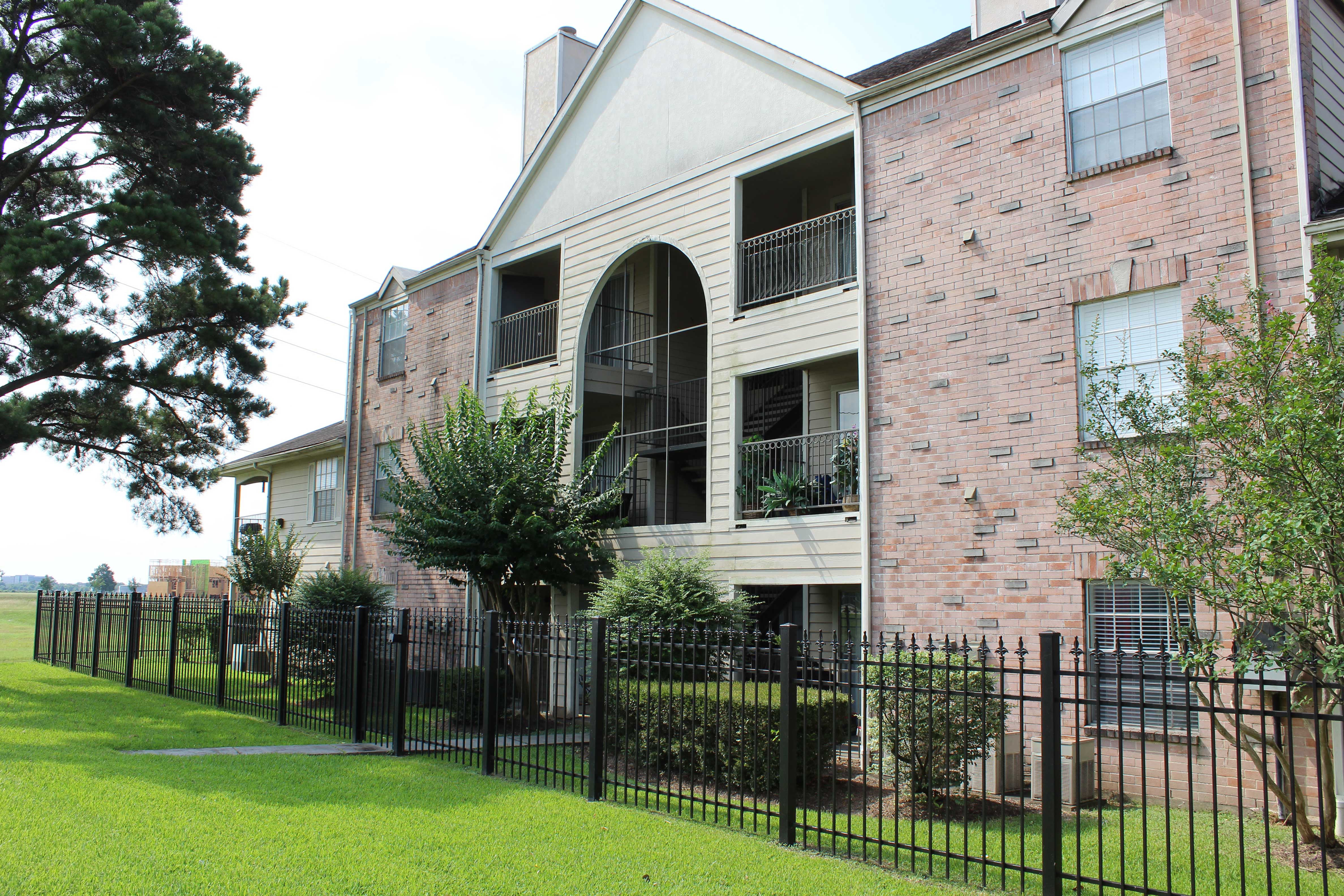 an apartment building with a yard and a wrought iron fence