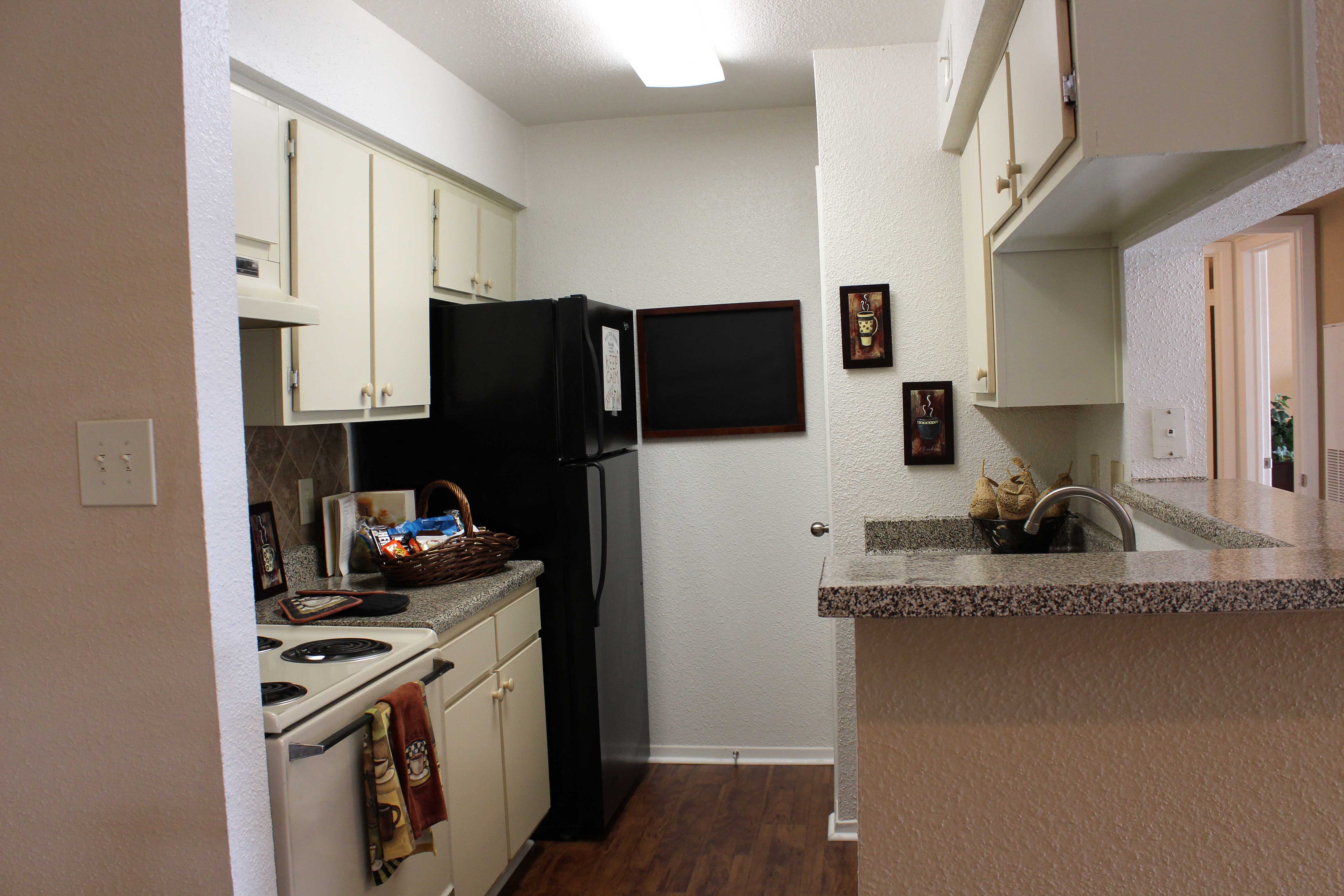 a kitchen with white cabinets and a black refrigerator