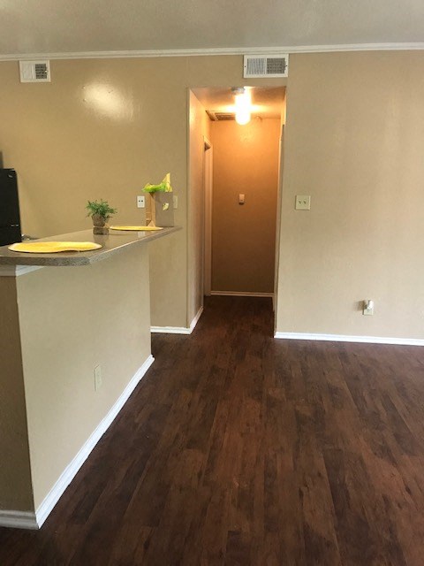 an empty room with a kitchen and a door to a hallway