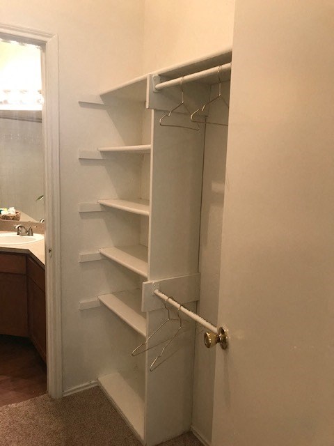 a white closet with shelves in a bathroom