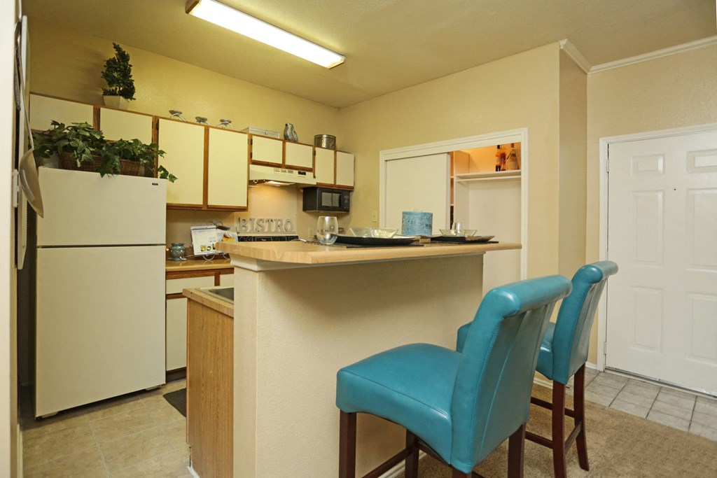 a kitchen with a bar and blue chairs