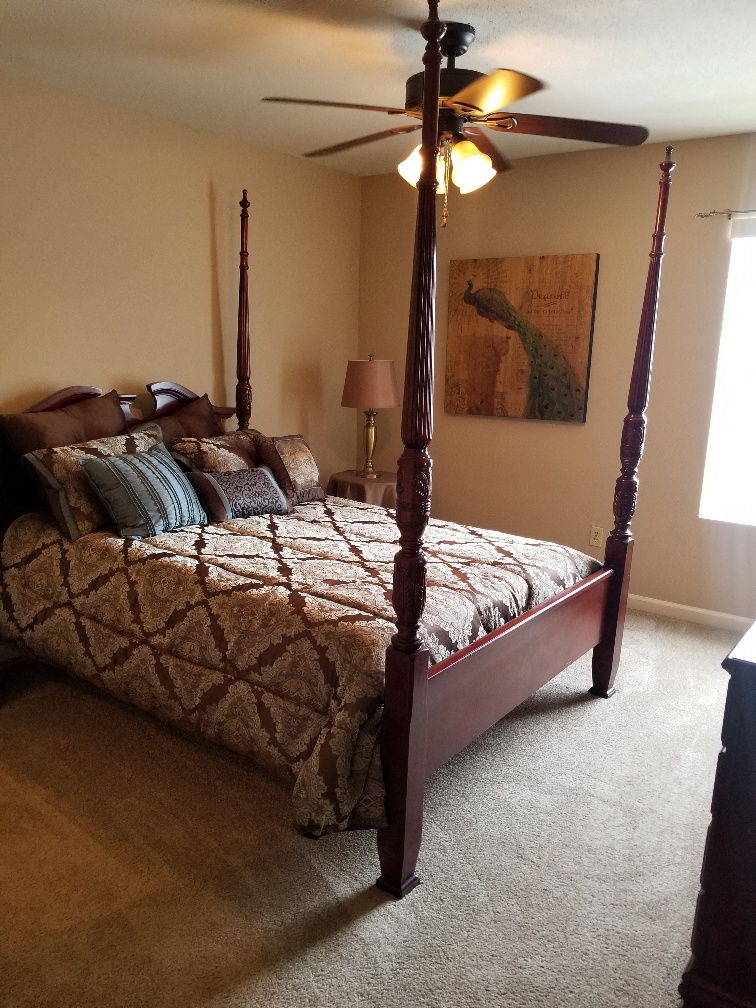a bedroom with a four poster bed and a ceiling fan