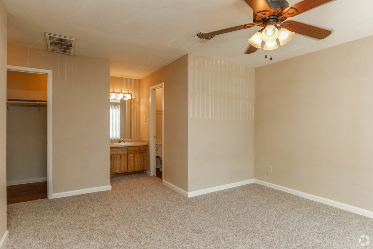 an empty living room with a ceiling fan and a bathroom