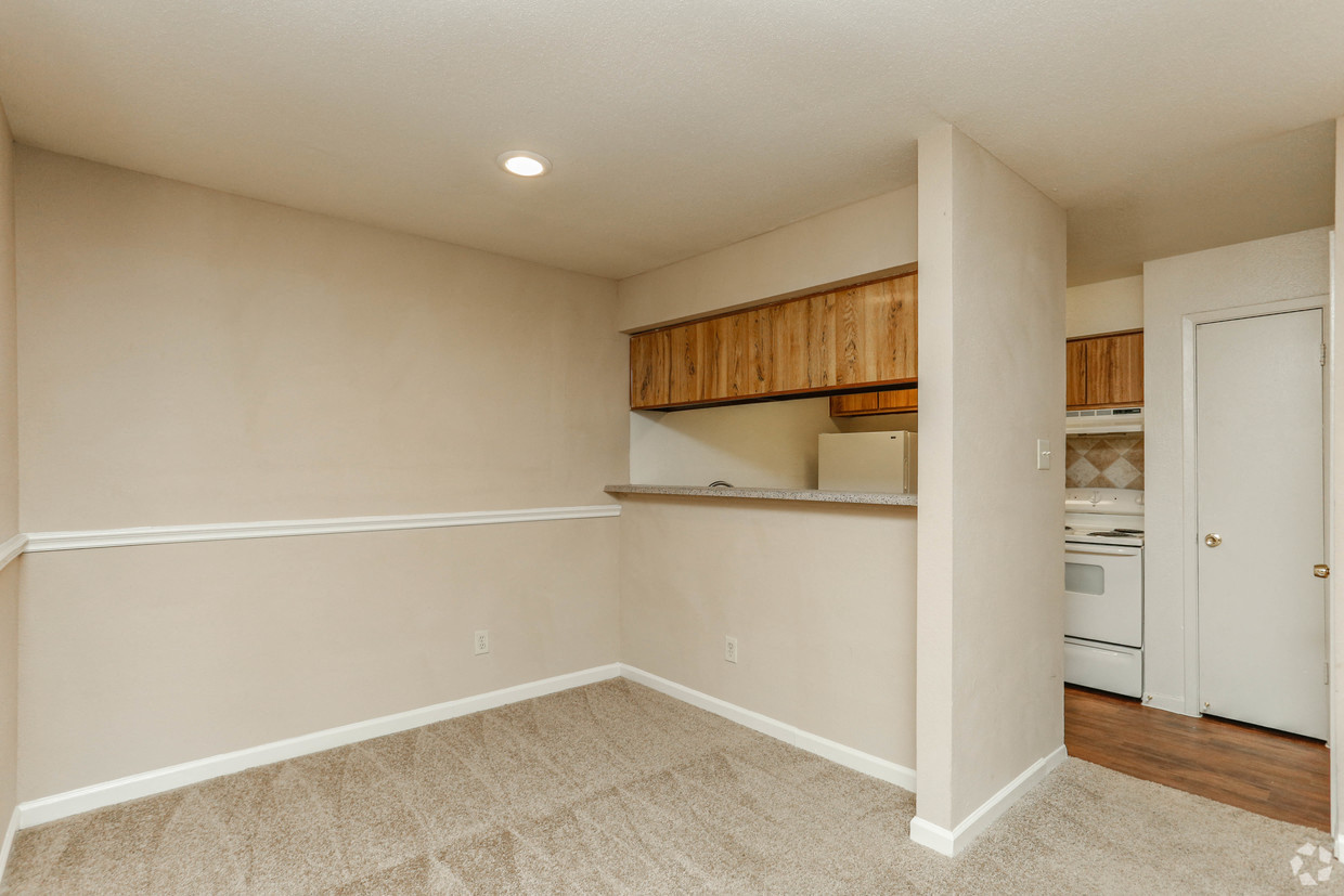 an empty living room and kitchen with a stove and refrigerator