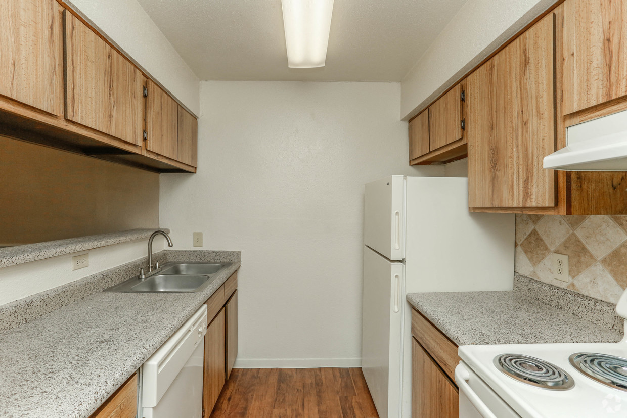 an empty kitchen with wood cabinets and white appliances