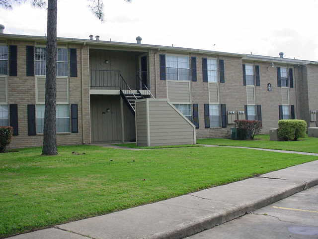 an apartment building with stairs and a green lawn