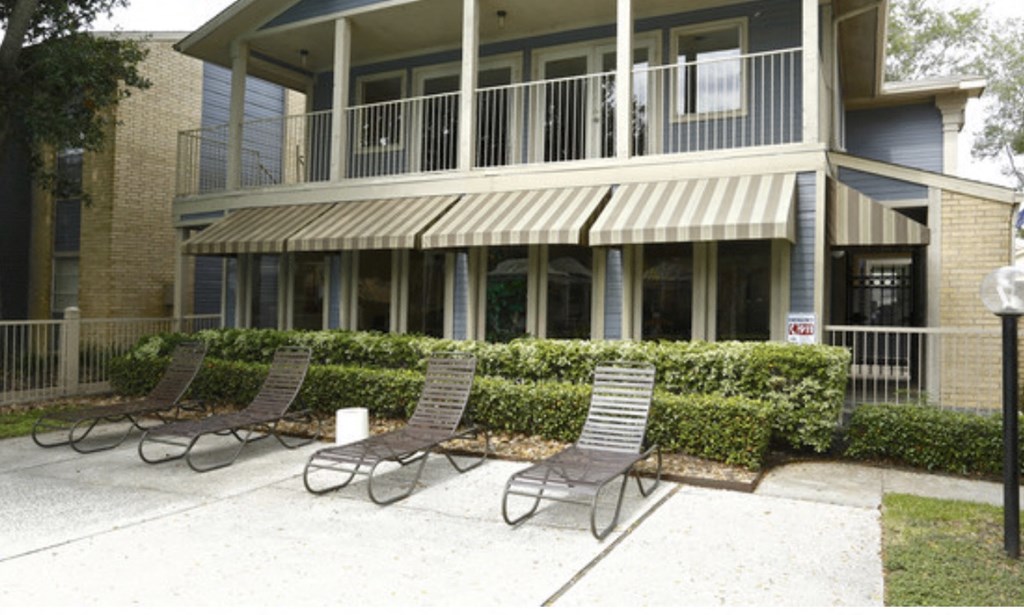 a patio with three chairs in front of a building