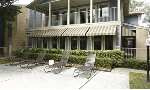 a patio with three chairs in front of a building