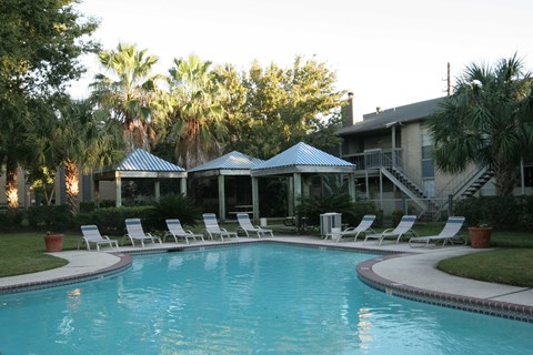 a large swimming pool with lounge chairs in front of a house