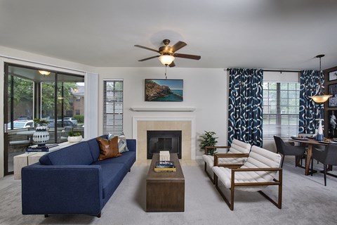 A living room with a blue couch, a fireplace, and a painting on the wall.