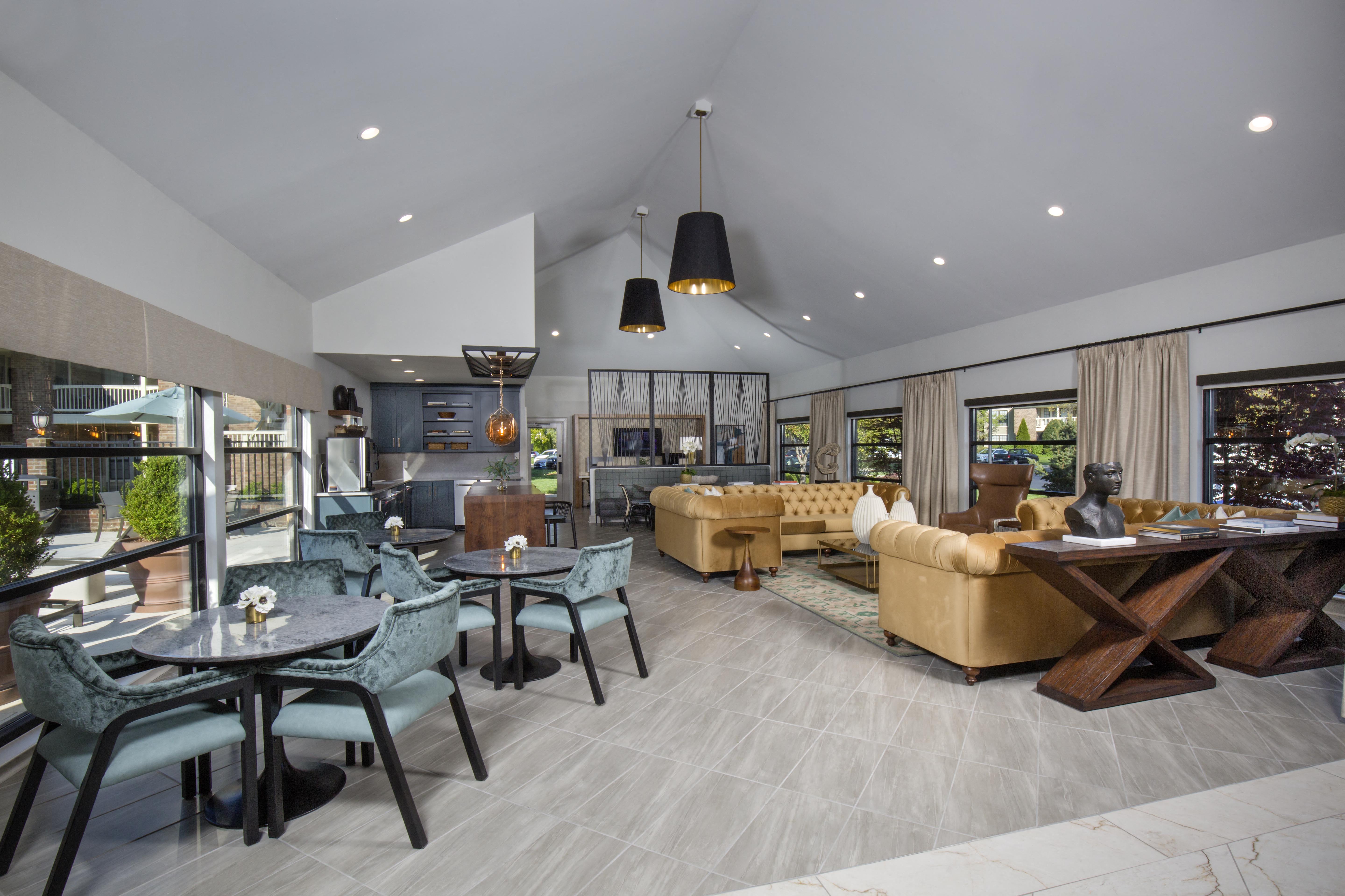 a living room with couches tables and chairs and a kitchen