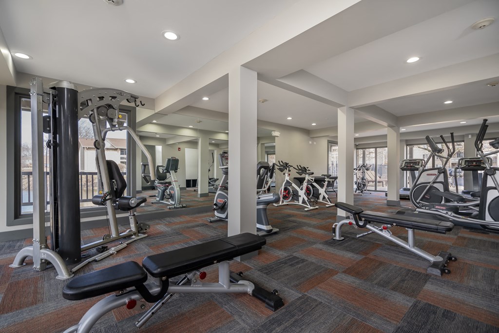 a gym with exercise equipment and weights in a building with windows