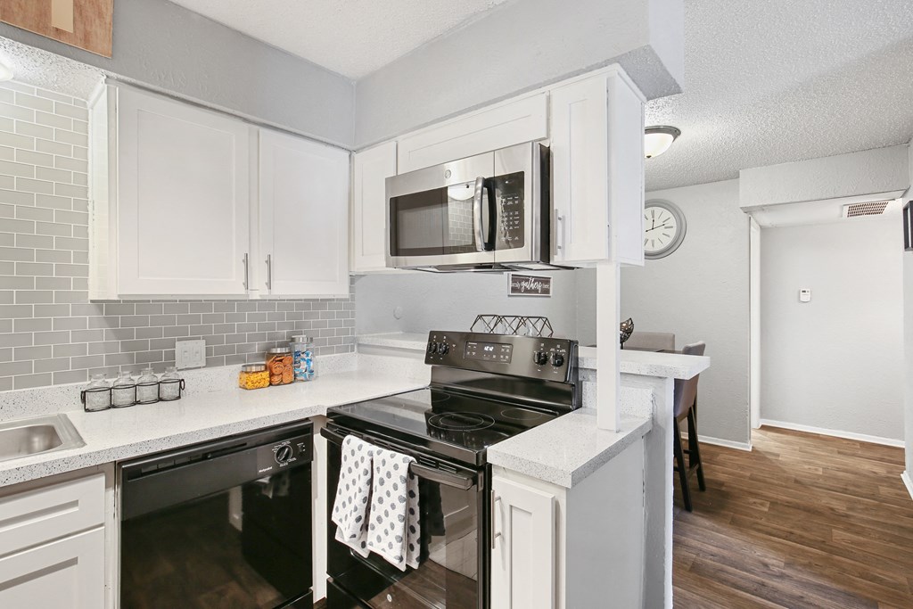 a kitchen with white cabinets and a stove and microwave