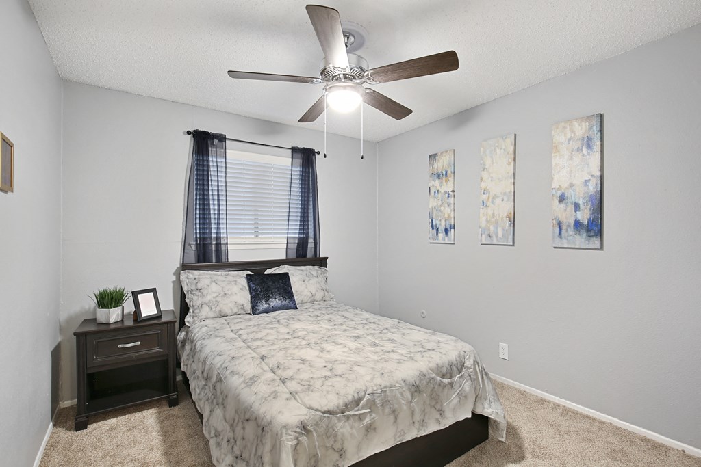 an empty bedroom with a bed and a ceiling fan