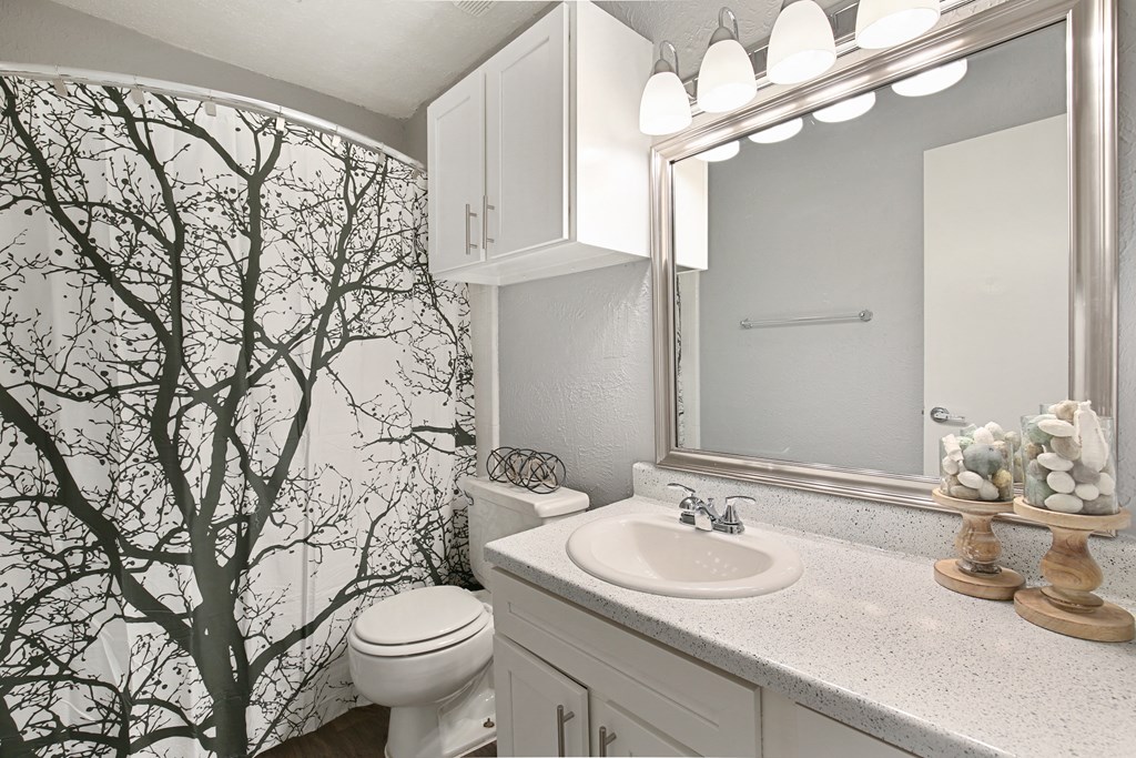 a white bathroom with a tree painted on the wall