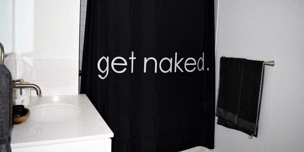 a bathroom with a black shower curtain that says